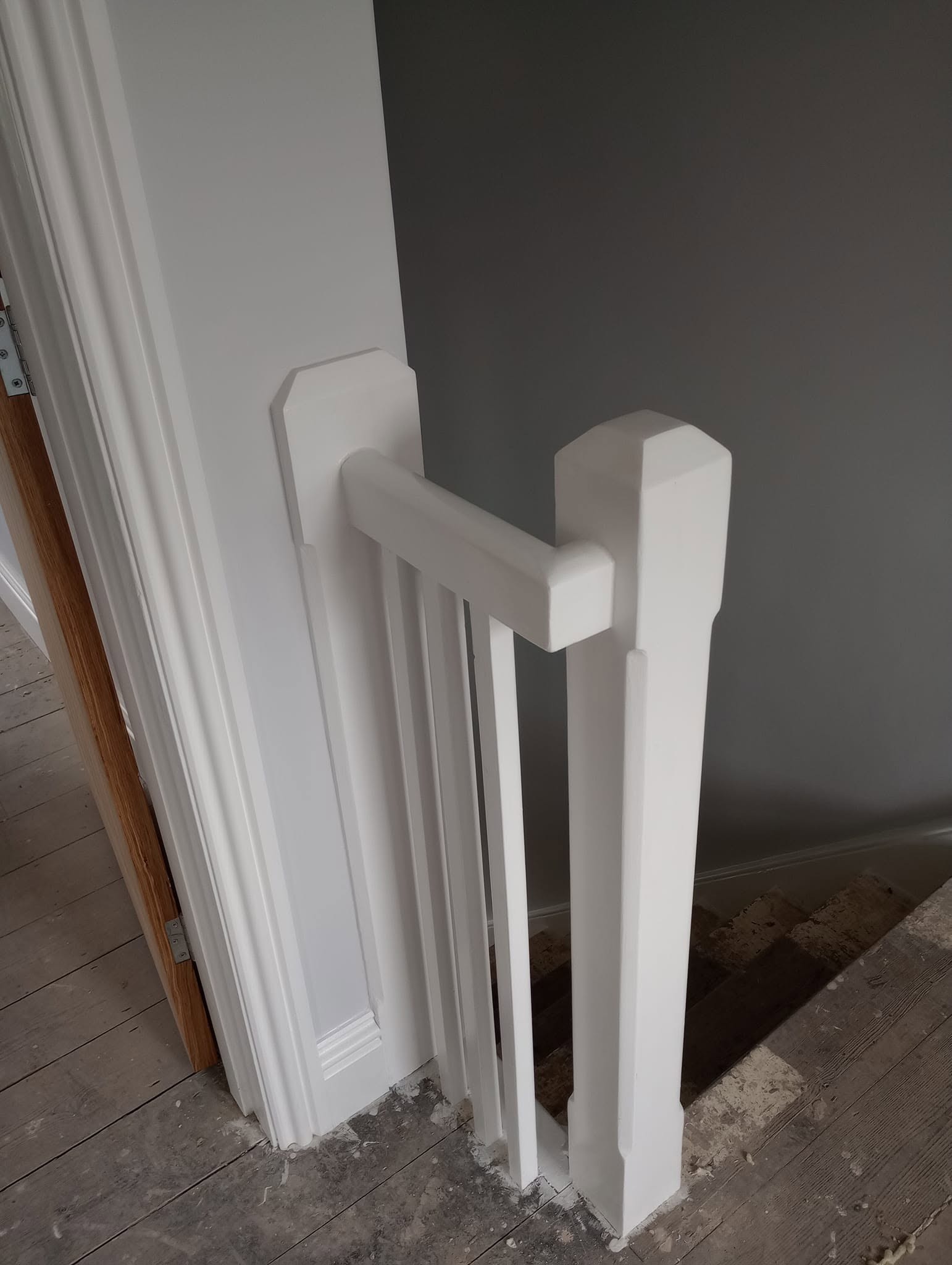 Newel post and spindles painted white beside a grey wall