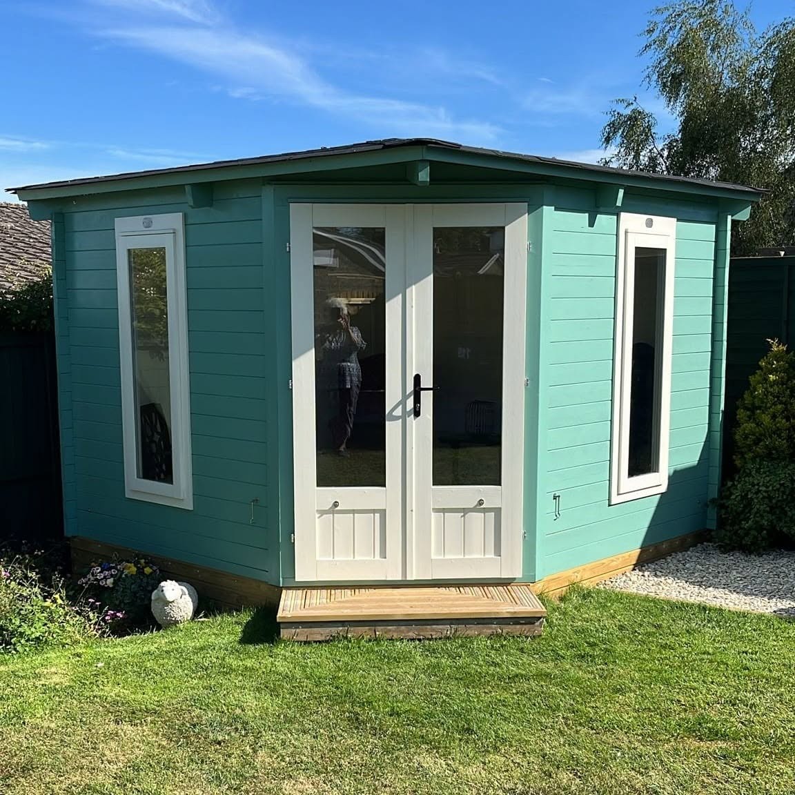 The same summerhouse painted teal with white doors and window frames