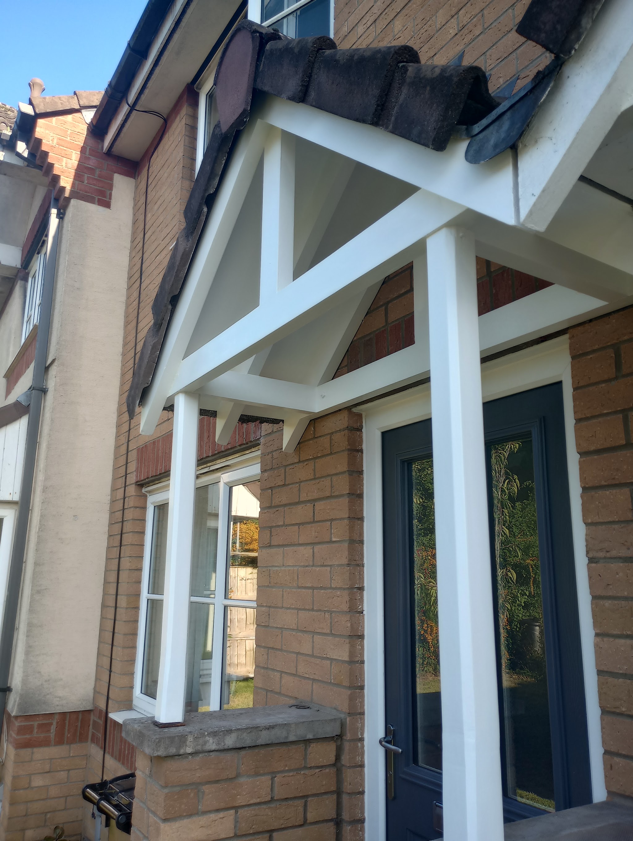 White timber porch over a grey front door, freshly painted
