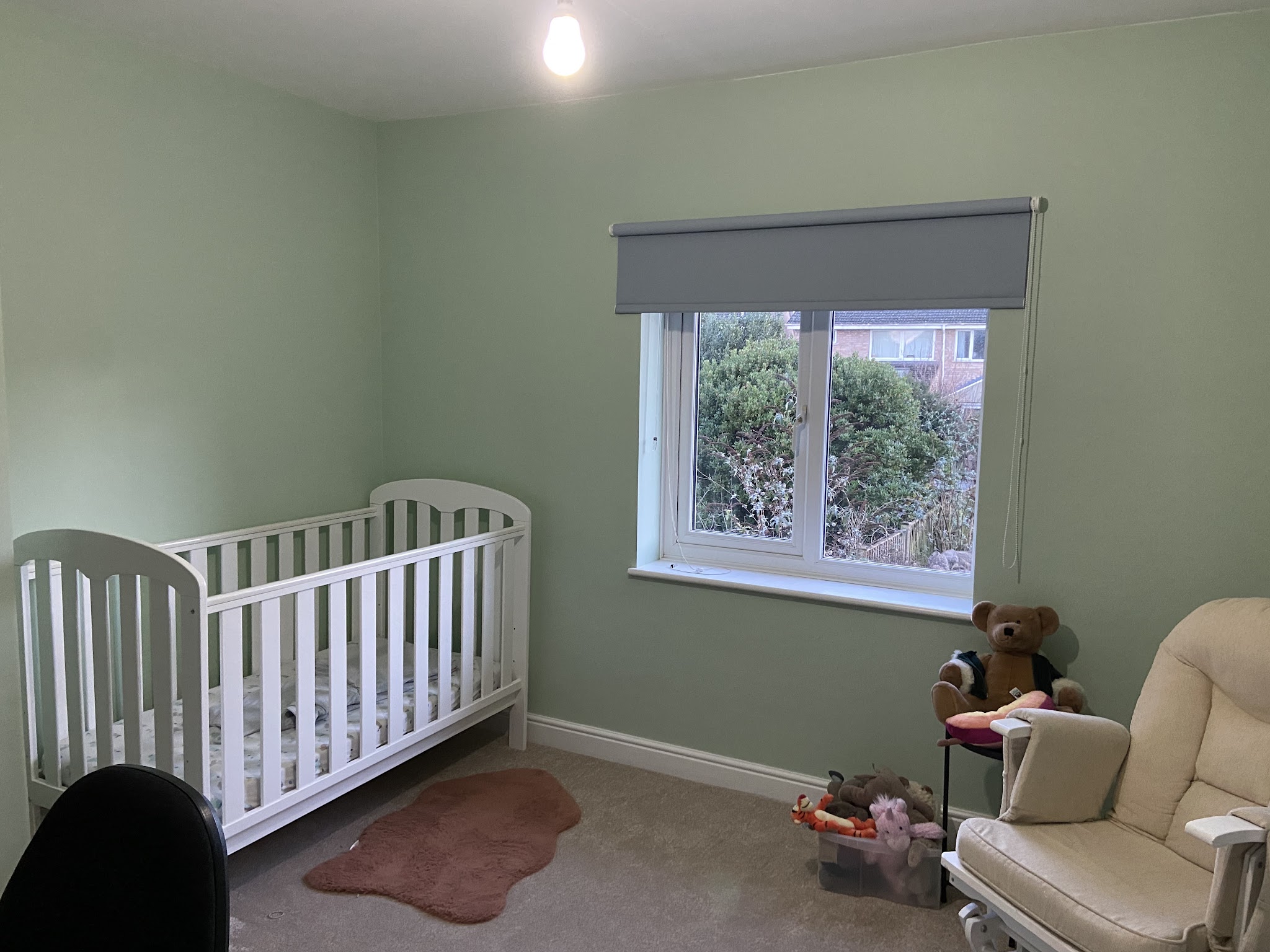 Sage green nursery with a white cot