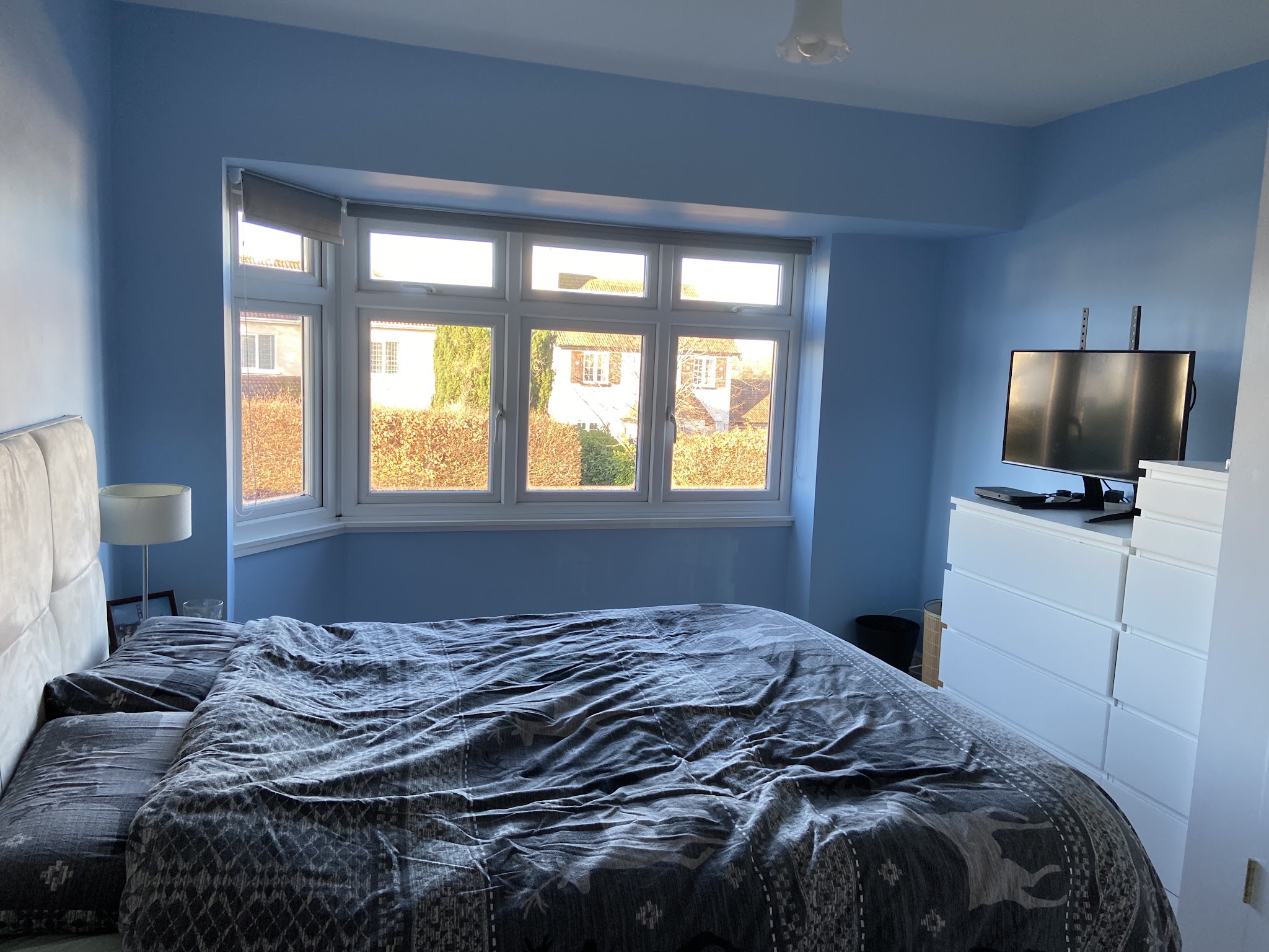 Bedroom in mid blue with a white bay window